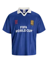 Camiseta de estilo polo con cuello camisero, manga corta y calce relajado. Presenta un diseño en color azul con estampado frontal "FIFA WORLD CUP" y detalles gráficos en contraste. Confeccionada en tejido técnico de poliéster reciclado.