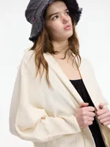 Cardigan de tejido de punto color beige, con cuello chal, manga amplia y bolsillos laterales.