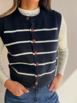 Chaleco tejido de punto con diseño de rayas horizontales en color marrón y blanco, con cierre frontal de botones y cuello redondo.