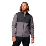 Campera cortaviento Columbia modelo Ascender, confeccionada en tejido softshell con tecnología Omni-Shield repelente al agua. Presenta diseño bicolor en tonos gris y grafito, cuello alto con protector de mentón, cierre frontal completo, bolsillos laterales y en el pecho con cremallera, y puños ajustables.