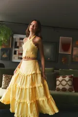 Falda larga de lino color salmón, con diseño de múltiples niveles de volados que aportan volumen y movimiento. Presenta una cintura ajustada y caída fluida.