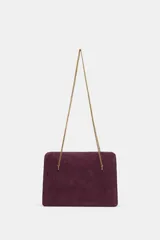 Bolso de hombro rígido de piel color bordó, con diseño de pespuntes, triple compartimento y cierre magnético. Cuenta con doble asa de cadena metálica dorada.