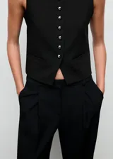 Pantalón de vestir negro de corte wide leg, con tiro medio, detalle de pinzas frontales y cierre con botón, gancho y cremallera.