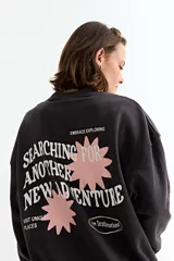 Buzo de cuello redondo y mangas largas, confeccionado en tejido de algodón y poliéster. Presenta un diseño liso en el frente con un pequeño detalle en el pecho y un corte holgado con puños y ruedo acanalados.