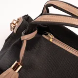 Cartera negra con textura tejida, doble asa corta y correa larga desmontable. Incluye un charm de flecos color beige.