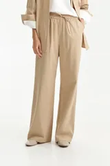 Pantalón largo de corte recto y calce relajado en color beige. Presenta cintura elástica con cordón ajustable y bolsillos laterales. Confeccionado en una mezcla de tencel y algodón.