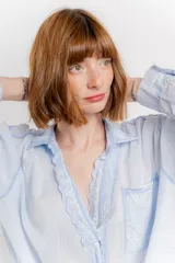 Camisa color crema de algodón con cuello camisero, botones y detalles de encaje en el escote.