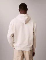 Buzo con capucha de Calvin Klein en color beige, confeccionado en mezcla de algodón y poliéster. Cuenta con bolsillo tipo canguro frontal, cordones ajustables y el monograma de la marca bordado en el pecho.