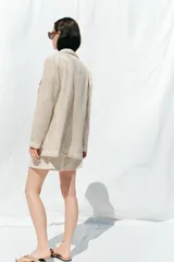 Blazer color crudo con diseño troquelado, cuello solapa, manga larga y bolsillos delanteros de plastrón.