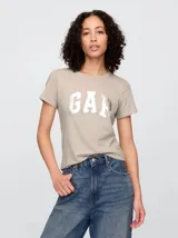 Remera de algodón color beige con cuello redondo, mangas cortas y logo de la marca estampado en el frente en color plateado.