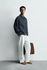 Cazadora regular fit color azul marino, confeccionada en tejido de lino con efecto ligeramente lavado. Presenta cuello solapa, manga larga con puño abotonado, bolsillos de vivo en la cadera y un bolsillo interior. Cierre frontal con cremallera.