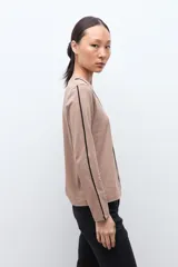 Remera de manga larga color tostado con escote en V y detalles de vivos en contraste color negro que recorren el frente y los laterales de las mangas.