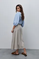 Falda midi color beige de tiro alto y silueta amplia, confeccionada en tela liviana con pinzas en el frente, pasacintos y bolsillos laterales.