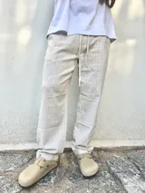 Pantalón de lino beige y crudo a rayas, de corte ancho y relajado.