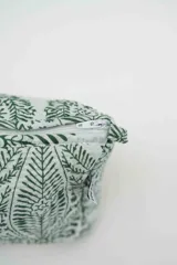 Neceser rectangular con cierre superior, confeccionado en tela acolchada con estampado botánico en color verde sobre fondo blanco.