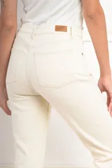 Pantalón de jean color crudo, tiro alto, corte flare y ruedo desflecado.