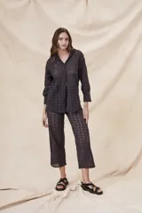 Camisa negra de algodón con bordado calado, corte oversize, cuello clásico, cierre frontal con botones y mangas largas con puños abotonados.