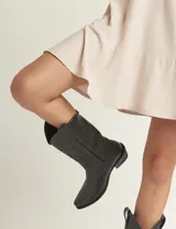 Botas de cuero color marrón y blanco con bordados negros, de estilo cowboy con taco bajo.