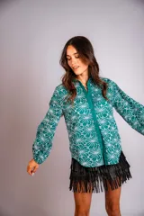 Camisa de manga larga con diseño abullonado, confeccionada en tela bordada con motivos florales. Presenta cierre frontal con botones y puños elásticos.