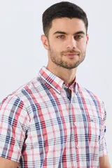 Camisa sport de manga corta con estampa de cuadros, combinando líneas rojas y azules sobre fondo blanco. Posee cuello con botones y cierre frontal abotonado.