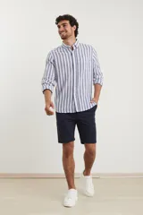 Camisa de lino a rayas verticales color beige y blanco, de manga larga con cuello abotonado y bolsillo en el pecho.