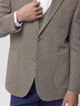 Blazer de tweed color azul marino con coderas en contraste, cierre frontal de botones y bolsillos laterales. Presenta un diseño clásico de corte regular.