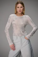 Blusa de manga larga confeccionada en tul semitransparente con estampado de efecto piel de cocodrilo y detalles brillantes. Presenta un corte ajustado al cuerpo y cuello redondo.