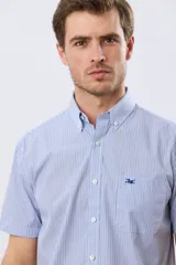 Camisa a cuadros de manga corta en tono celeste, con cuello abotonado y bolsillo frontal en el pecho que incluye un sutil bordado.