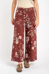 Jean de corte wide leg con tiro medio, confeccionado en algodón peinado. Presenta un diseño estampado con motivos florales sobre una base de color bordó.