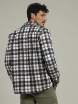 Sobrecamisa a cuadros azul, verde y blanco, con cuello camisero, cierre frontal con botones, dos bolsillos de parche con botón en el pecho y puños abotonados.