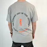 Remera gris de algodón con estampa circular en el pecho con texto y logo en color naranja.