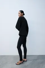 Leggings negros de tiro alto con bolsillos falsos de vivo en el delantero y cierre lateral con cremallera oculta. Presentan cremalleras ocultas en los bajos.