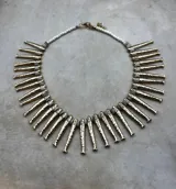 Collar dorado con dijes en forma de peces y cuentas blancas.