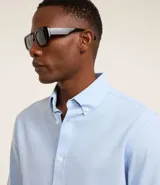 Camisa blanca de corte regular, confeccionada en tejido Oxford de algodón, con cuello inglés, mangas largas y cierre frontal abotonado.