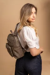 Mochila mediana de cuero sintético con textura rugosa, cuenta con dos compartimentos frontales con cierre, asa superior y correas ajustables.