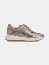 Sneaker de mujer con acabado metalizado en tono dorado, diseño con perforaciones decorativas en los laterales y cordones al tono. Presenta una suela de plataforma blanca con efecto moteado y base de goma color caramelo.