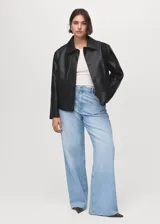 Chaqueta corta de efecto piel en color negro, con cuello de solapa, cierre frontal de botones y dos bolsillos de parche con solapa en la parte delantera. Presenta un diseño recto y forro interior.