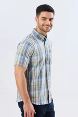 Camisa sport de manga corta con estampa a cuadros en tonos celestes, amarillos y blancos, con cuello camisero abotonado y bolsillo frontal en el pecho.