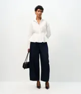 Pantalón de jean azul oscuro con corte barrel, tiro alto y diseño de piernas amplias con terminación afinada. Cuenta con cintura con pasadores, cierre frontal con botón y bolsillos funcionales.