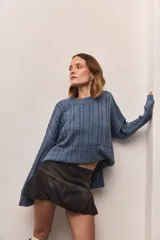 Buzo tejido azul con diseño de trenzas, cuello redondo y corte holgado.