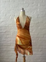 Vestido corto con estampado abstracto en tonos naranja, blanco y marrón. Diseño con escote halter y espalda descubierta.