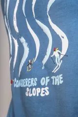 Remera de cuello redondo y manga corta en color azul, con un pequeño bordado de un pingüino esquiador en el pecho.