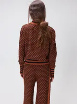 Sweater de tejido de punto jacquard con diseño geométrico, cuello redondo y puños acanalados en contraste de color verde y beige.