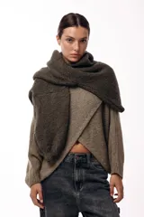 Sweater de punto con diseño cruzado frontal, de silueta amplia y mangas largas con puños ajustados. Presenta un corte holgado y textura suave.