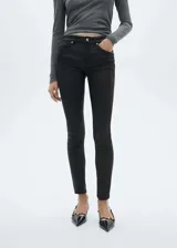 Pantalón jeans tipo skinny con acabado encerado, tiro bajo y diseño de cinco bolsillos. Confeccionado en tejido elástico con cierre de cremallera y botón.