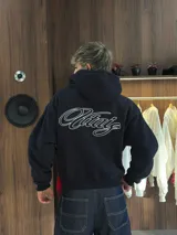 Hoodie negro con capucha y estampa gráfica blanca en la espalda con diseño tipográfico cursivo. Presenta puños y ruedo acanalados.