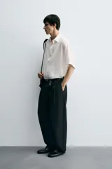 Camisa de corte relajado confeccionada en tejido fluido con textura acanalada. Presenta cuello solapa, manga corta y cierre frontal con botones.