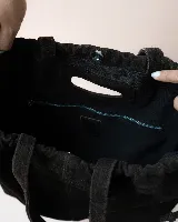 Cartera tipo tote de cuero color bordó, con diseño fruncido en los laterales y abertura central integrada como asa. Presenta una silueta flexible y espaciosa, ideal para uso diario.