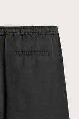 Pantalón de corte relajado confeccionado en una mezcla de algodón y lino. Presenta cintura elástica con cordón ajustable, bolsillos laterales y bolsillos traseros de vivo.
