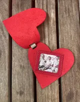 Llavero con forma de corazón de cuero gris con tira de cuero rojo y aro metálico.